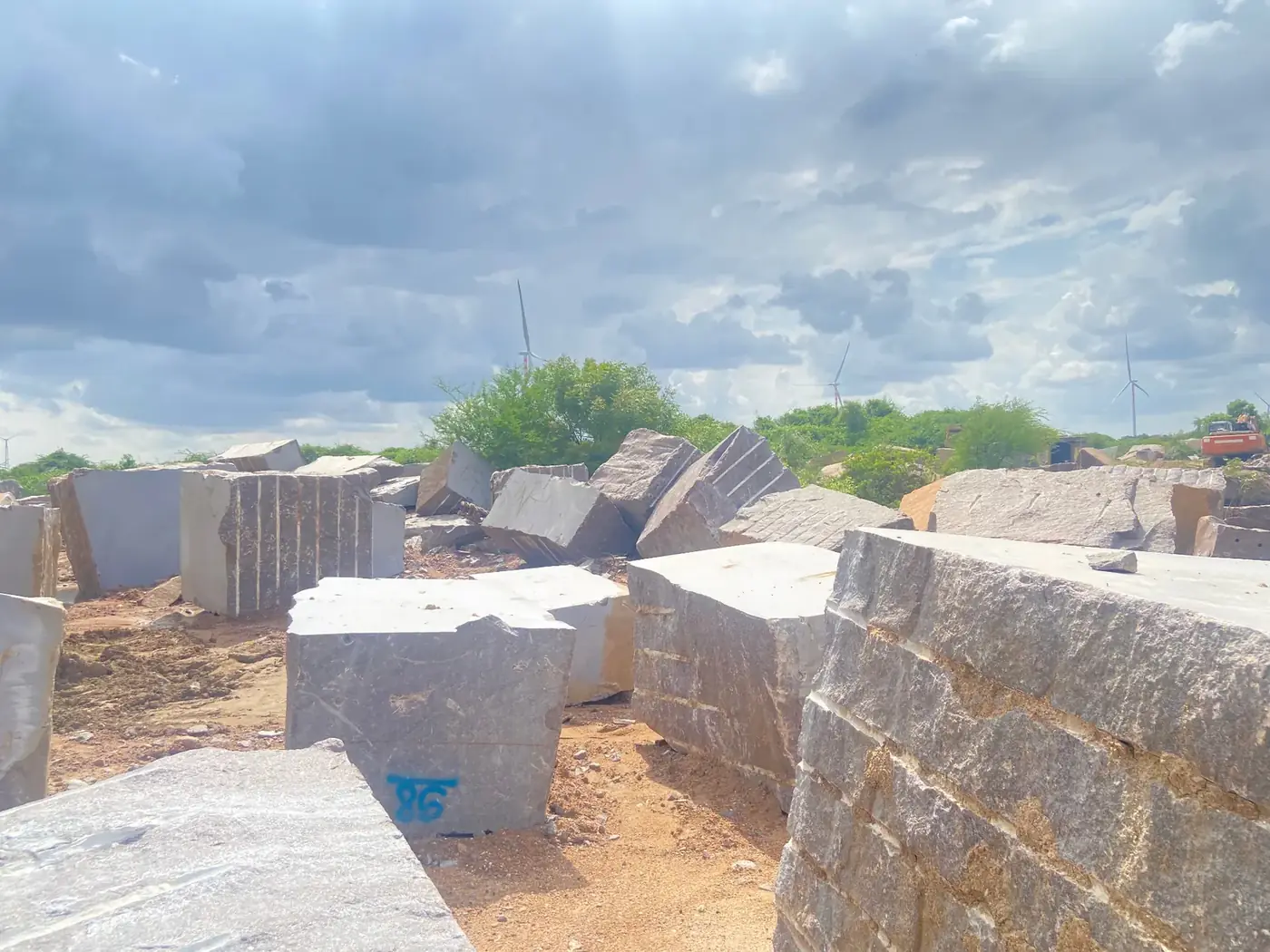 Large granite blocks across the quarry site under a cloudy sky